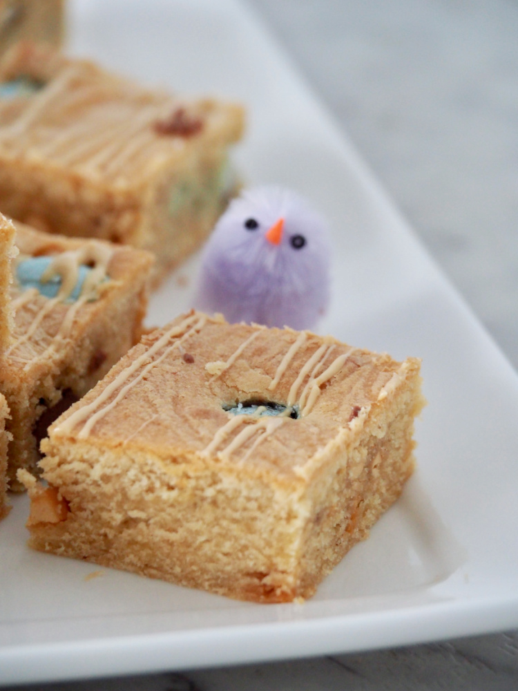 close up of a square of easter caramilk blondies with a purple decorative chick