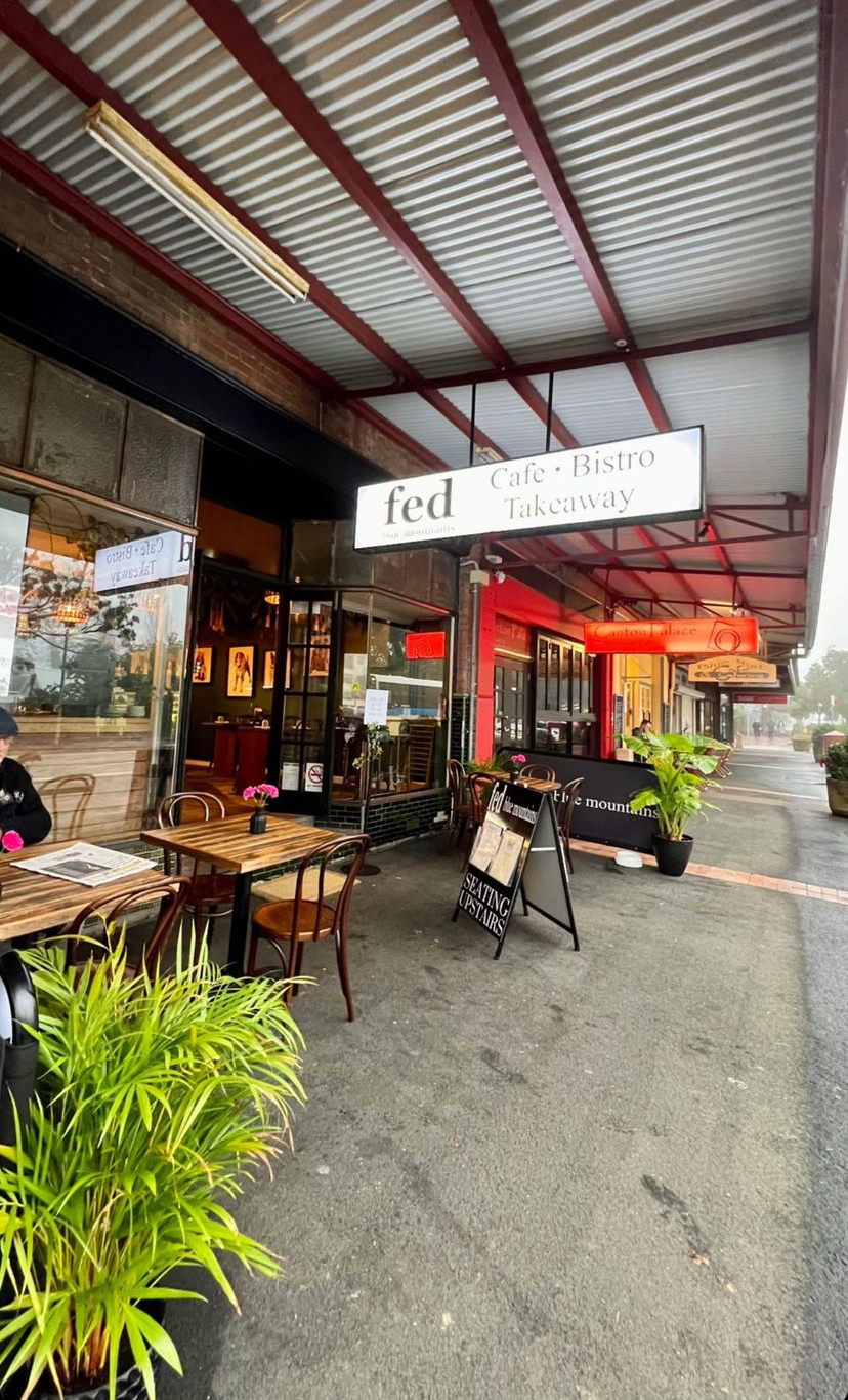 outside a cafe with green plants and pavement tables