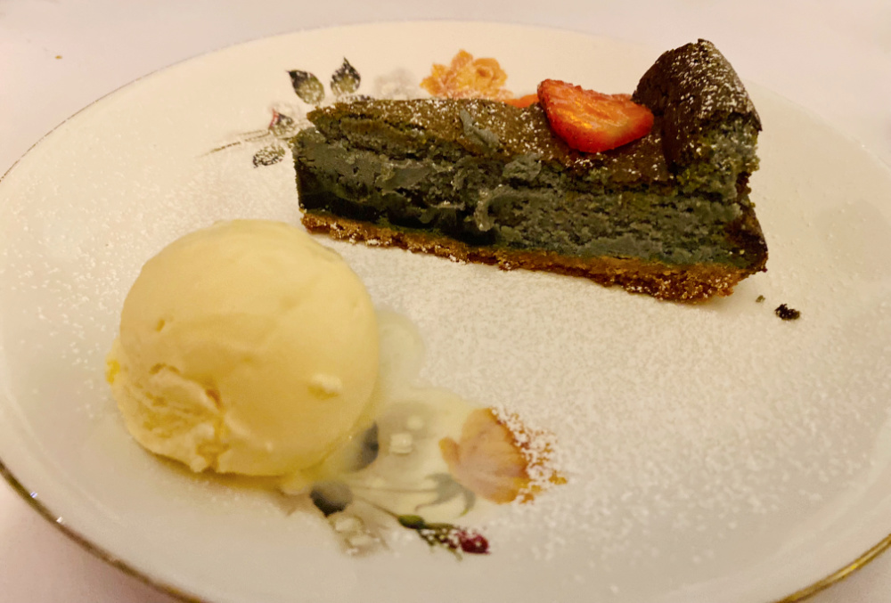  a slice of licorice cheesecake with a scoop of ice cream on a floral vintage plate