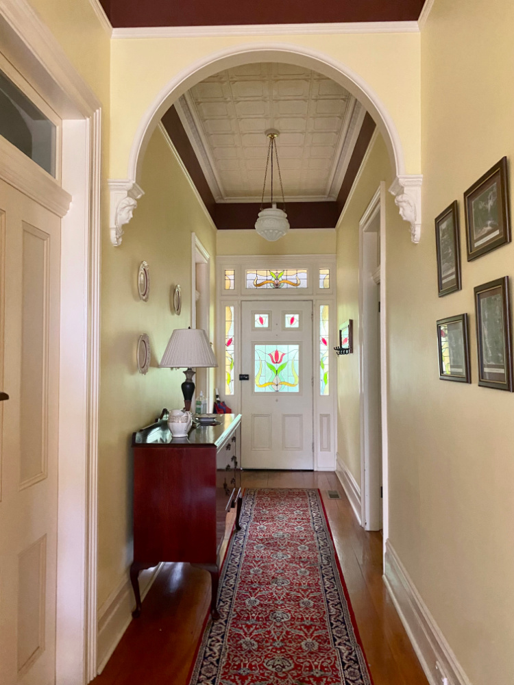 hallway of an old cottage looking down to a white door with stained glass panels