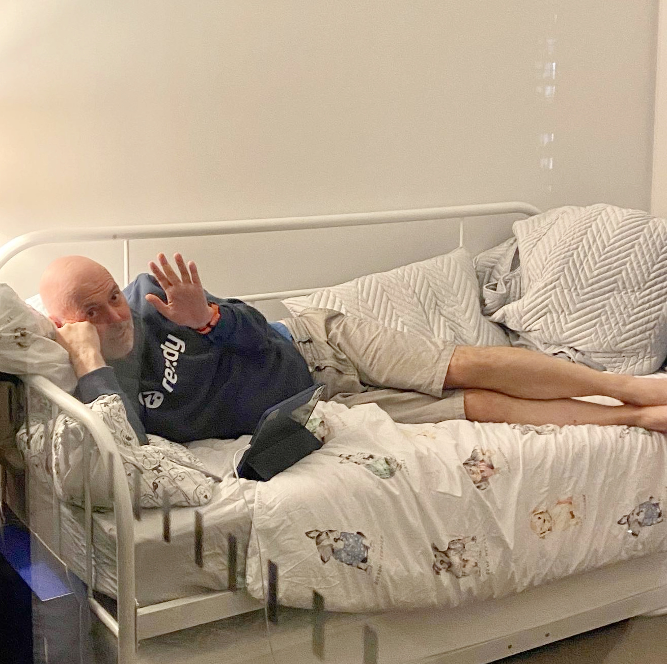 a man lying on a day bed and waving at someone through the patio door