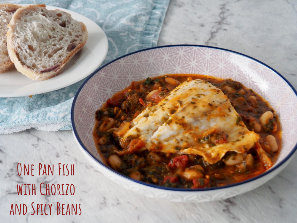 fish fillet on top of a bed of spicy beans next to a side plate with some slices of crusty bread