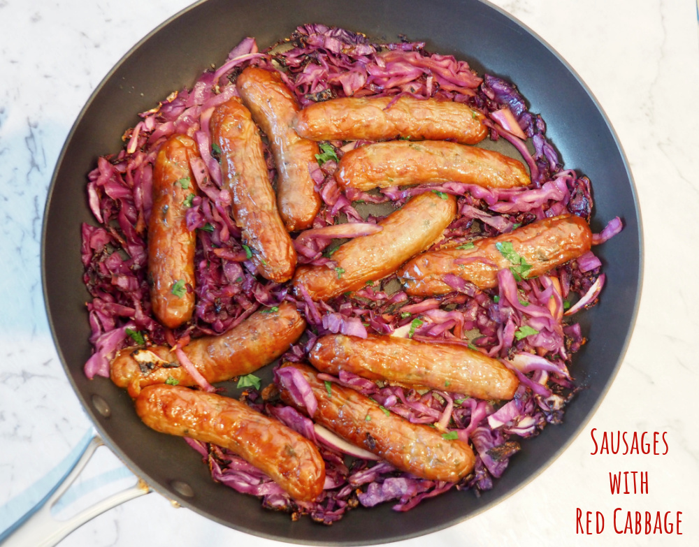 pan with sausages nestled in sliced red cabbage garnished with parsley