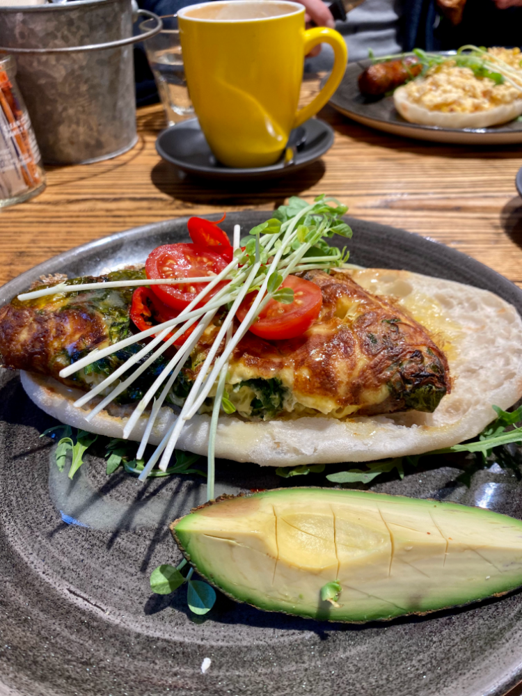 folded omelette topped with sliced red chilli, sprouts next to a generous wedge of avocado