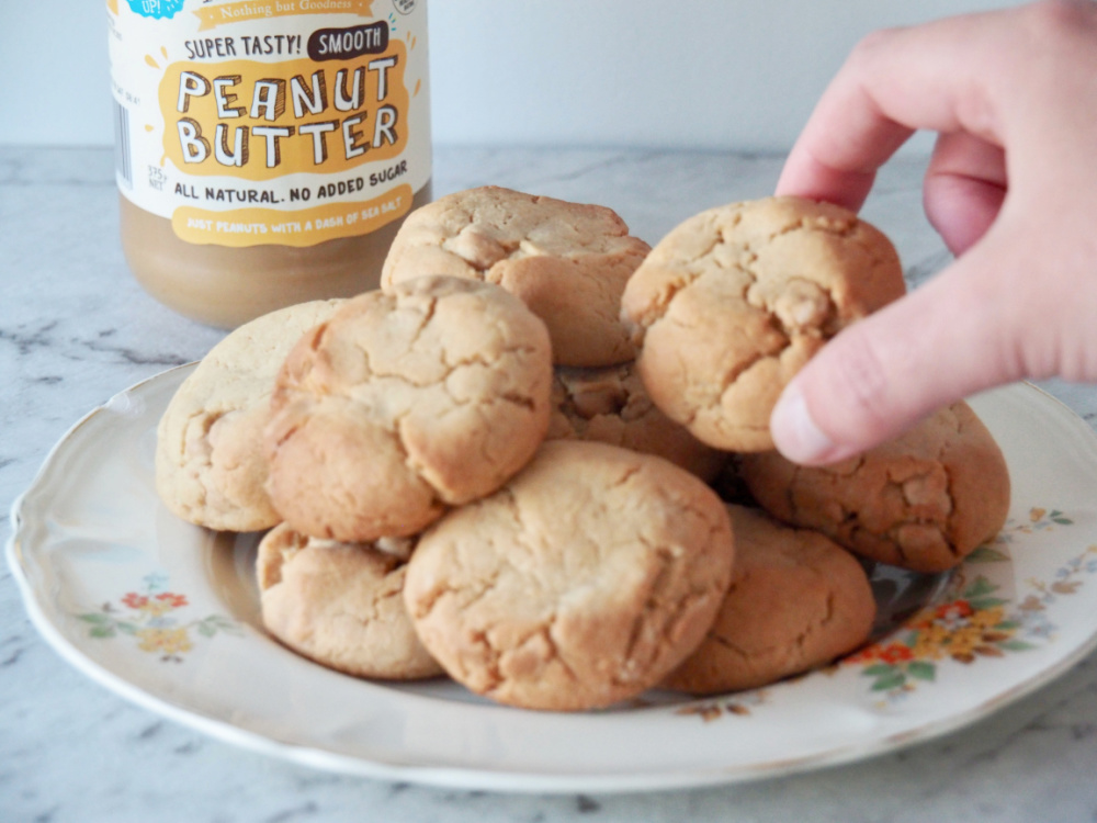 hand taking a peanut butter chip cookie off a plate