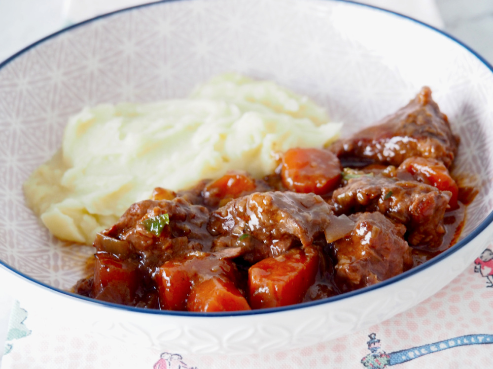 beef stew in shallow dish with a side of mashed potato