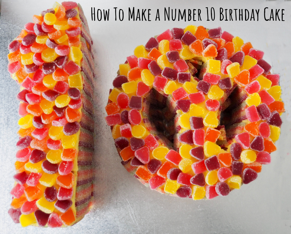 2 cakes made into the shape of a 1 and a peace sign covered in cut jubes and placed on a silver board