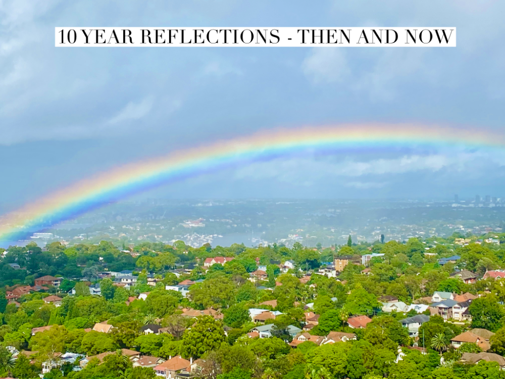 looking out over houses and trees with a big rainbow in a light blue sky