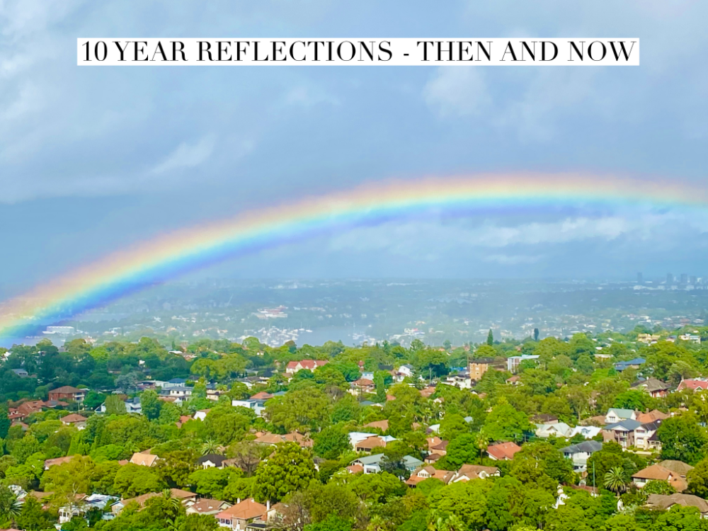 looking out over houses and trees with a big rainbow in  a light blue sky