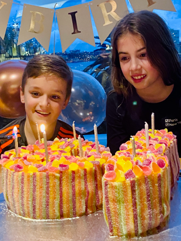 a boy and a girl looking at the candle lit on a number 10 birthday cake