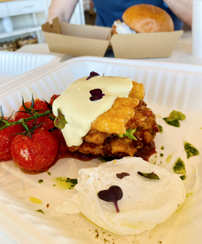 corn fritters with poached eggs, halloumi smashed avo and cherry tomatoes with hollondaise sauce on top