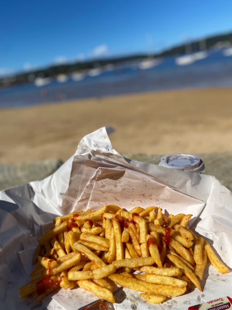 box of take away chips with sand and ocean blurred out in background