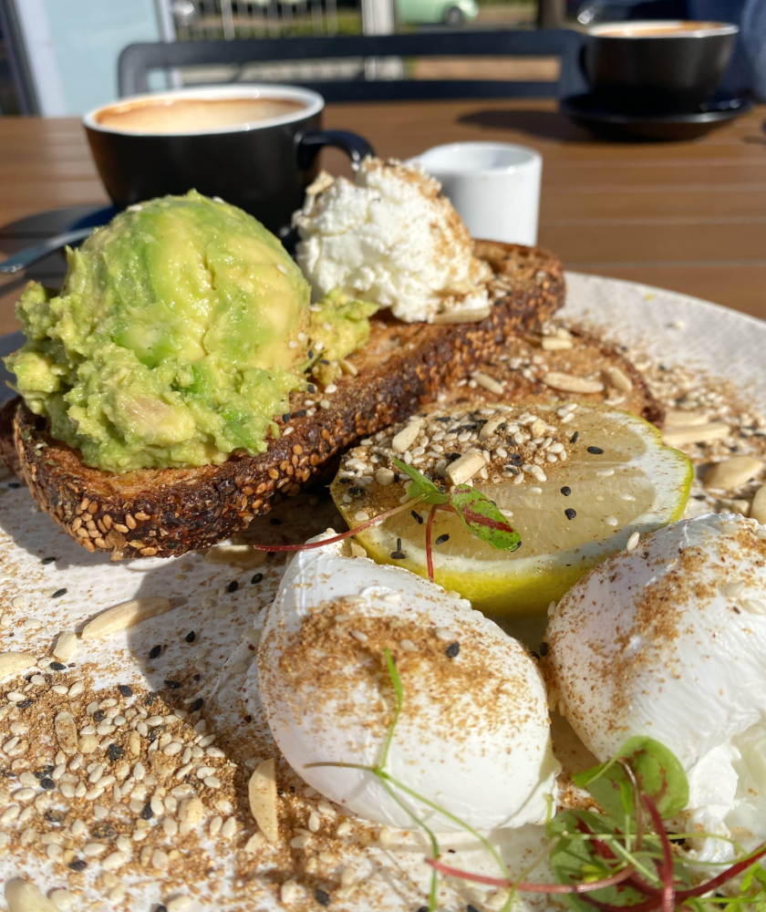 close up of plate with poached eggs, a slice of toast topped with scoop of smashed avo, chevre and all sprinkled with dukkah
