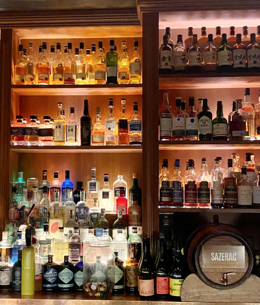 looking at the shelves behind a bar loaded with bottles of spirits