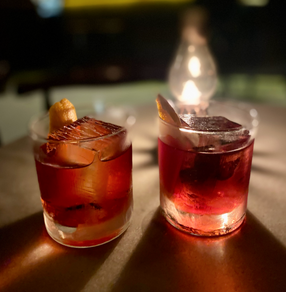2 negronis with a light behind