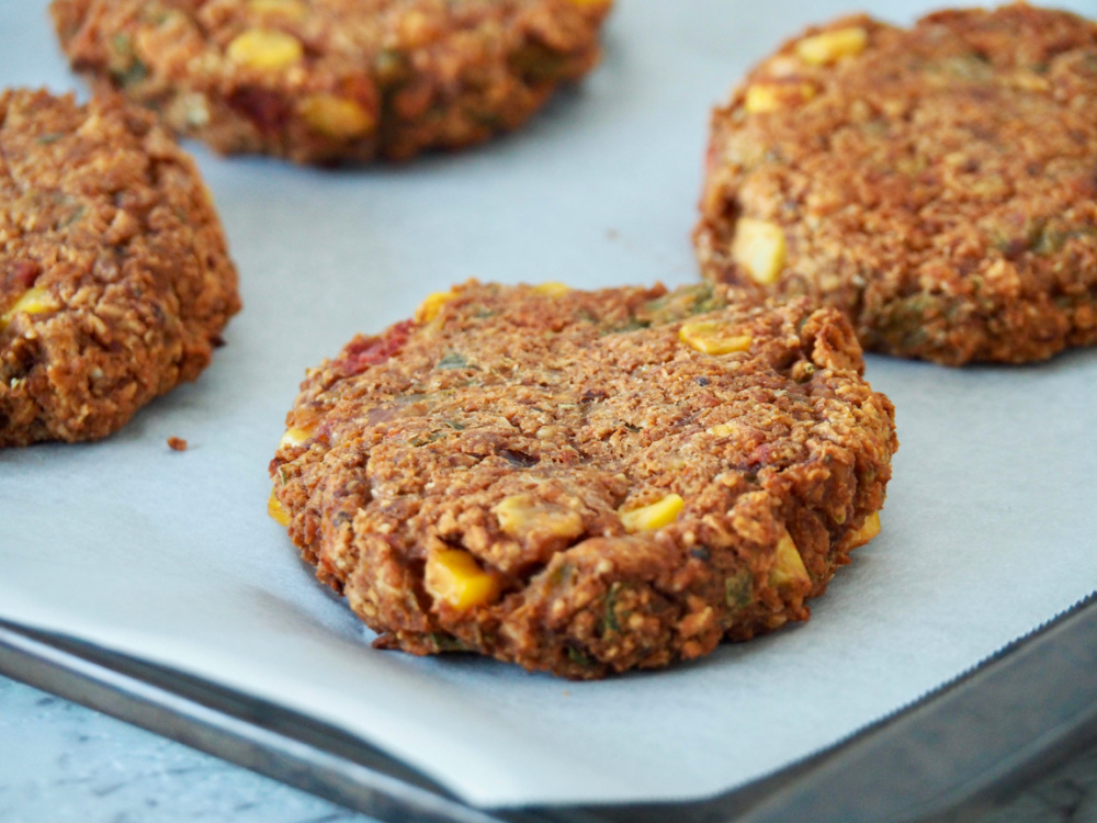 baked refried bean burgers on baking paper on baking tray