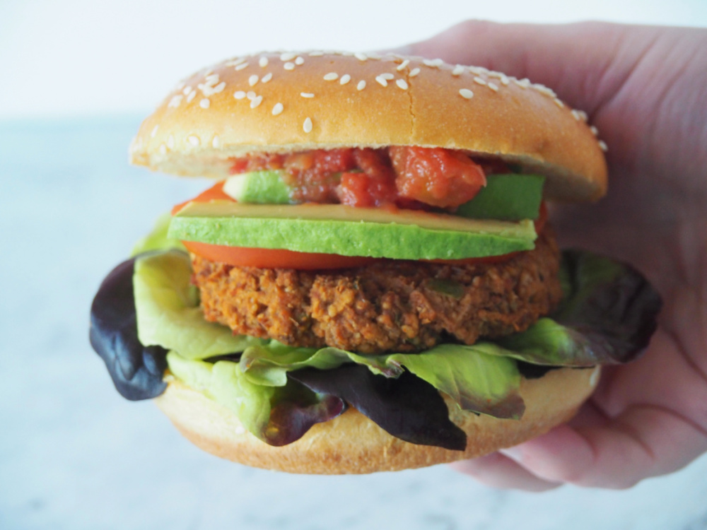 hand holding a refried bean burger in a bun