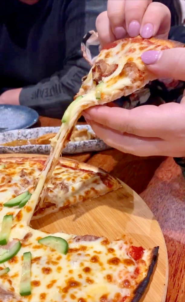 hand lifting up a slice of pizza with cheese stretching