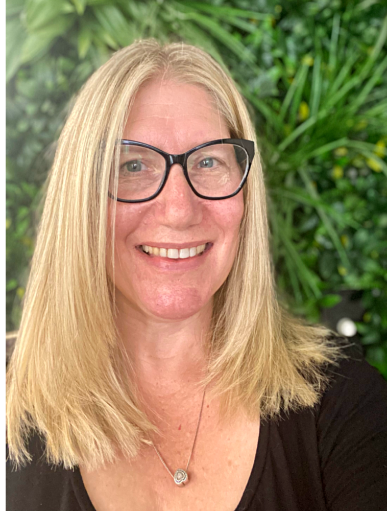 selfie of a woman with shoulder length highlighted blonde hair wearing glasses and smiling looking at camera