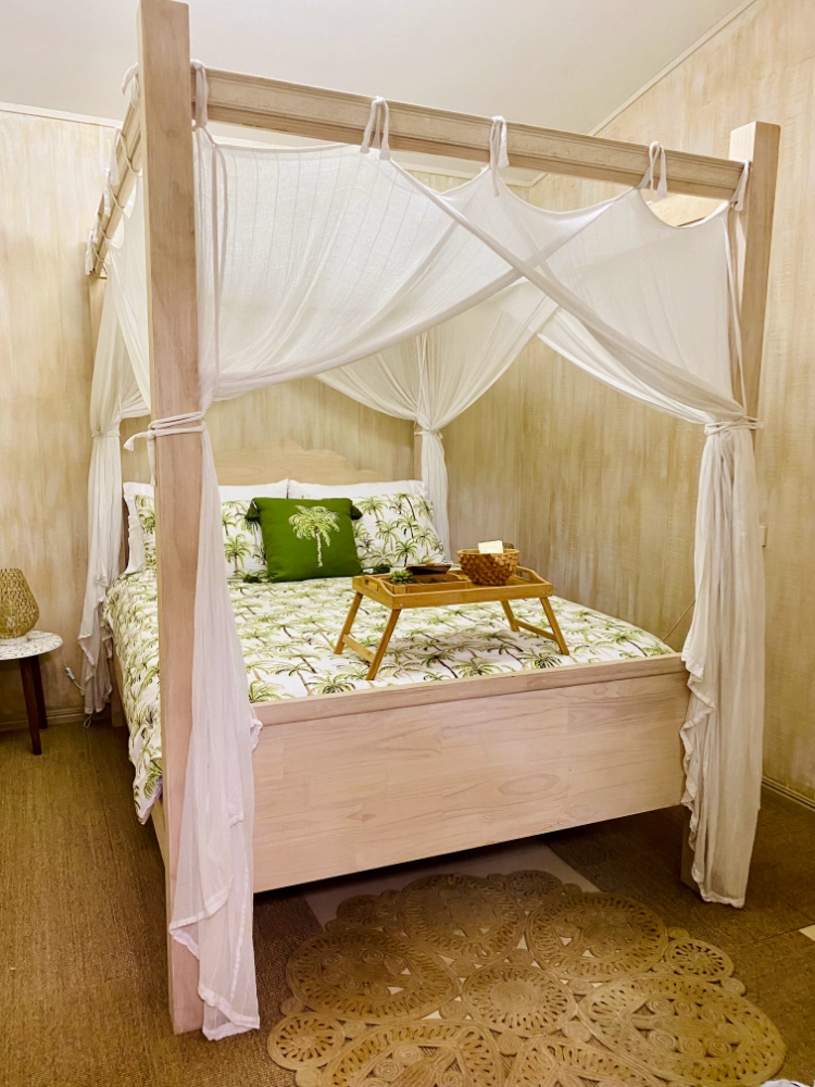 a tropical inspired four poster bed with white drapes