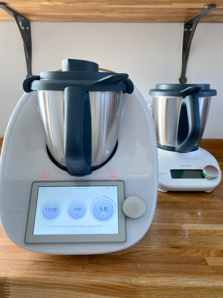 A thermomix and a smaller thermomix friend are standing on a wooden bench