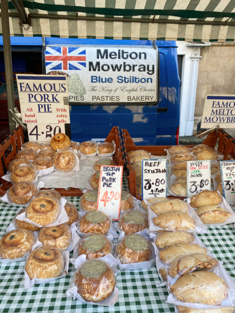 a market stall laden with pasties and different varieties of pork pies