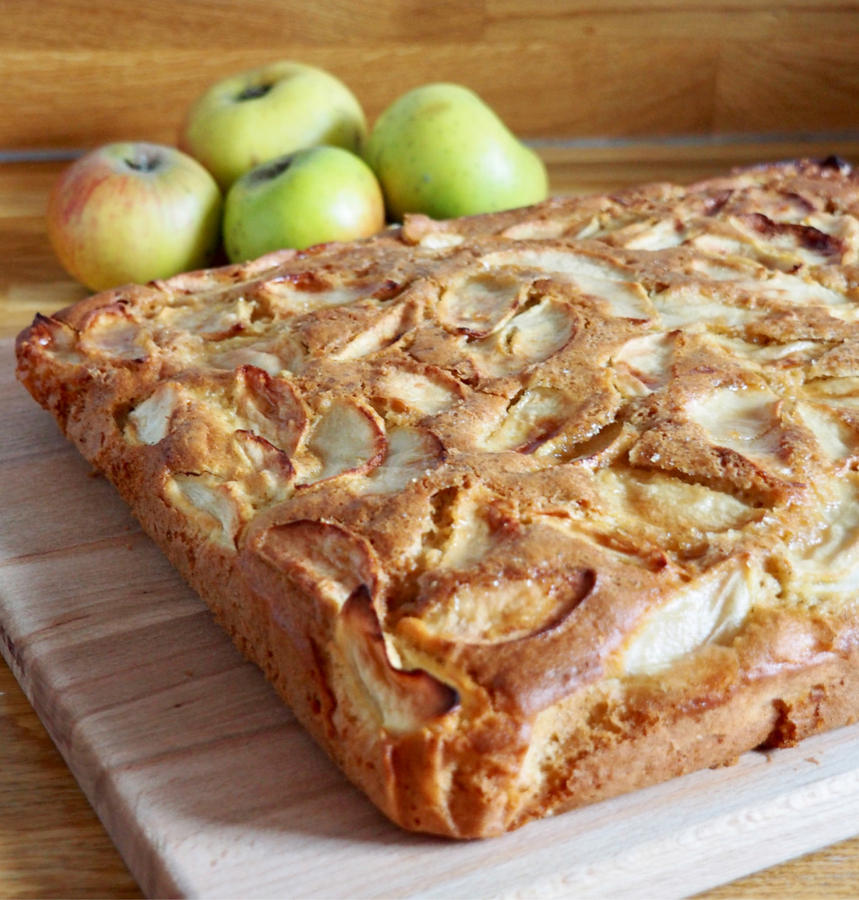 apple traybake on wooden chopping board with some apples in the background