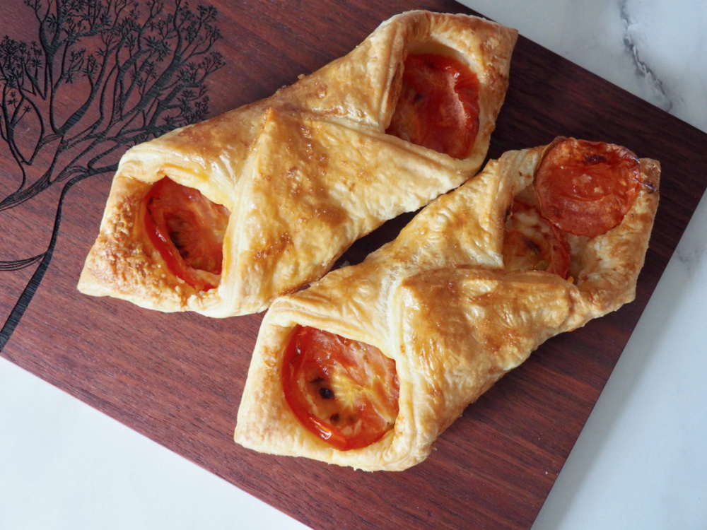 looking down on two cheesy turnovers on a dark wooden board