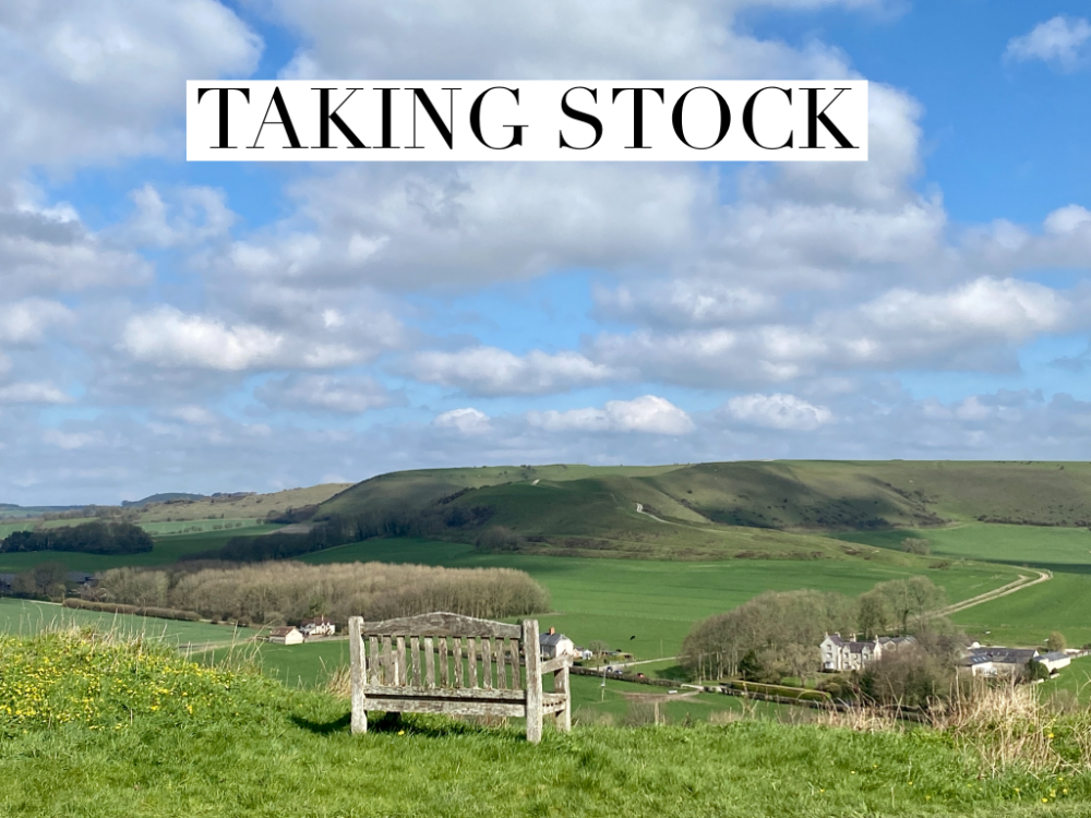 a wooden bench at the top of a hill looking over the landscape