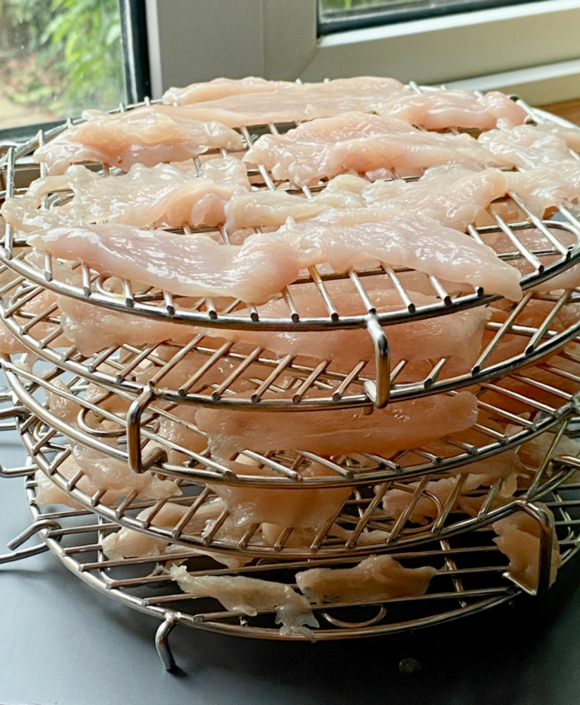 sliced chicken on racks ready to be dehydrated into jerky