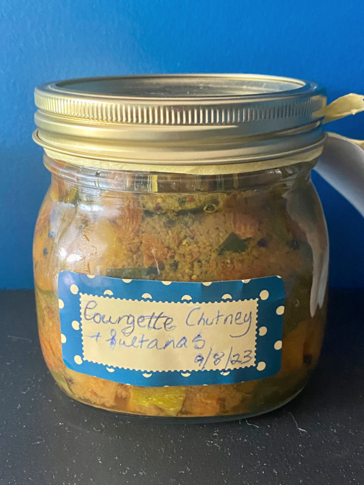 a jar of courgette chutney on a blue background