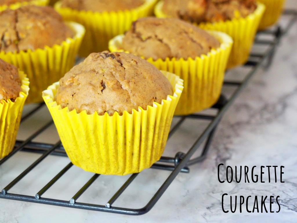 looking at a corner of a cooling rack with courgette cupcakes in yellow paper cases