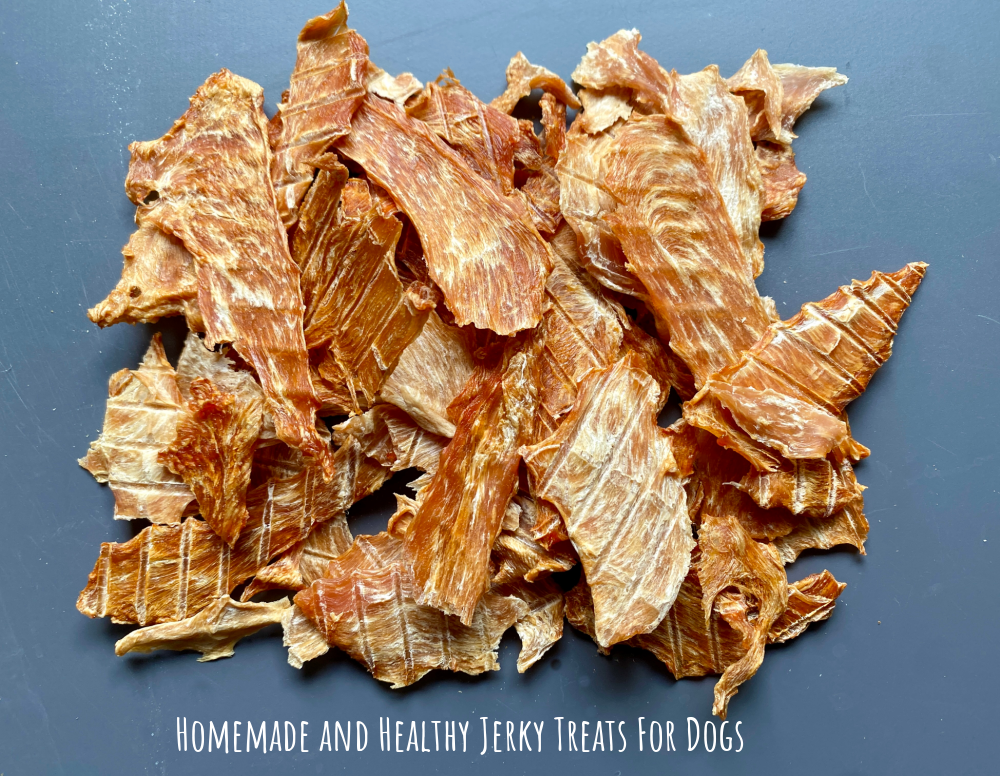 a pile of dehydrated chicken jerky on a black plastic chopping board