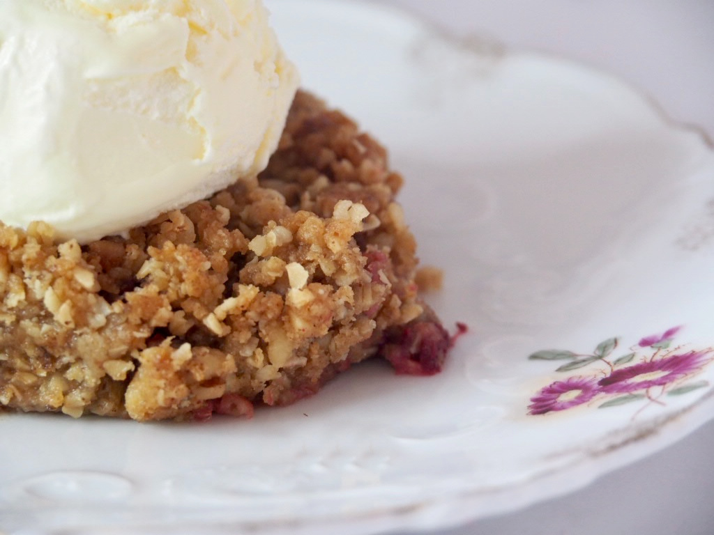 side view rhubarb crumble and ice cream on small white vintage plate with flowers