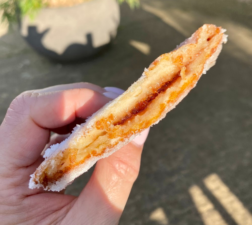 hand holding a deep fried jam sandwich cut in half