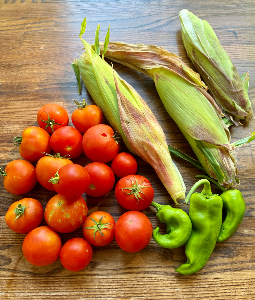 fresh tomatoes, fresh corn cobs and 3 large green chillies on wooden work surfac