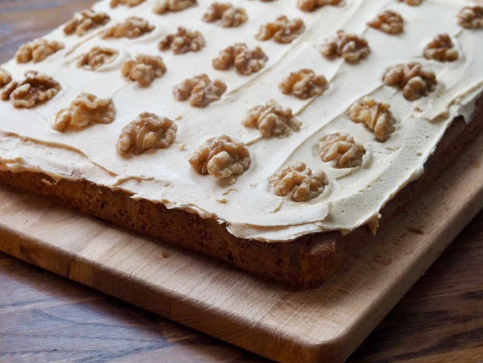 looking down on a coffee traybake uncut covered with fudge icing and topped with walnut pieces