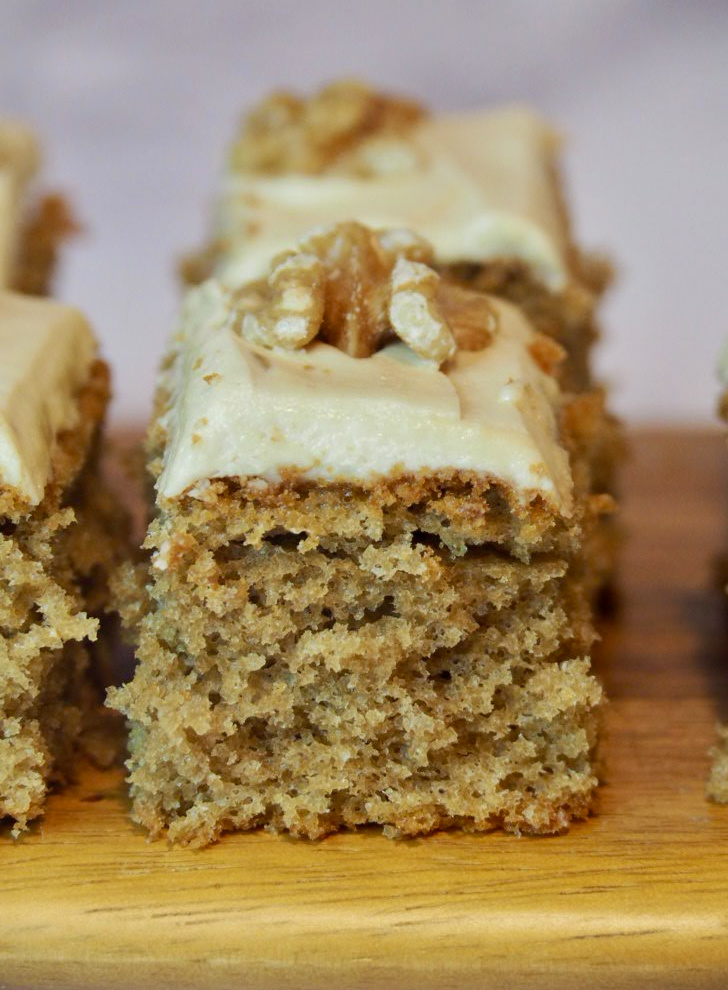 a square of coffee traybake topped with fudge icing and a walnut piece