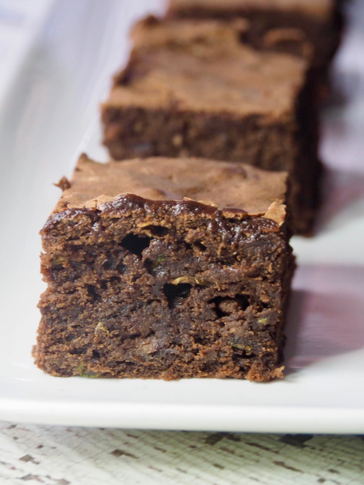 close up of fudgy zucchini brownies on a white platter