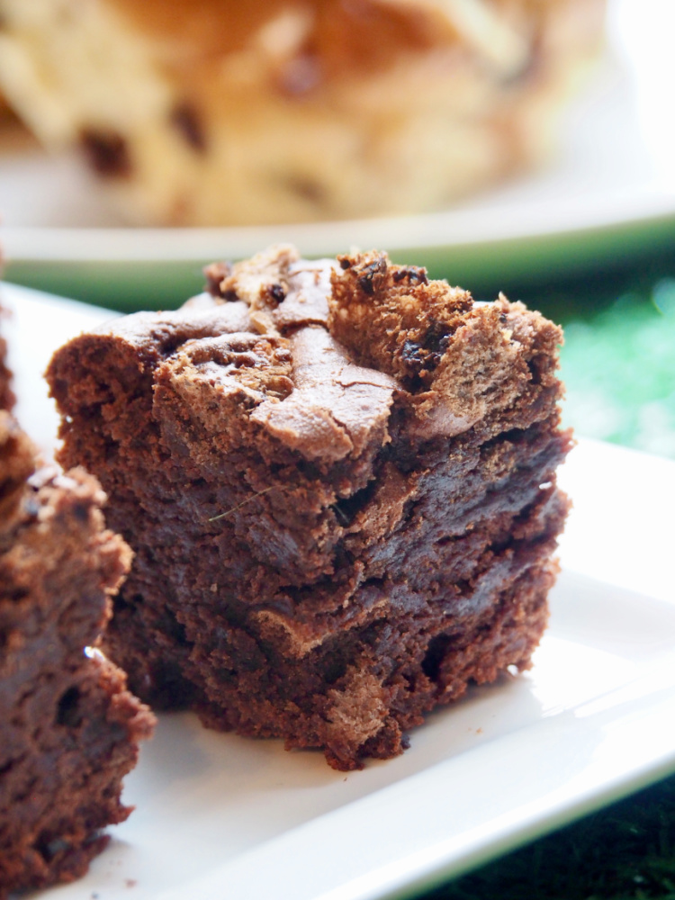 close up of double chocolate hot cross brownie with a faded out hot cross bun in the background